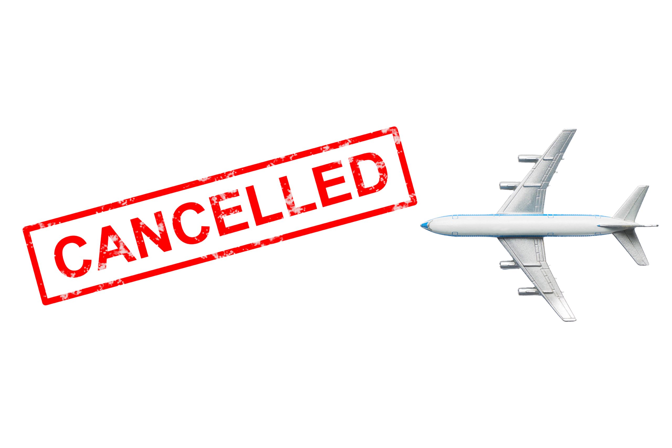 A top-down view of a small silver and white toy passenger airplane flying toward a bold red rectangular stamp that reads "CANCELLED," all isolated on a solid white background.